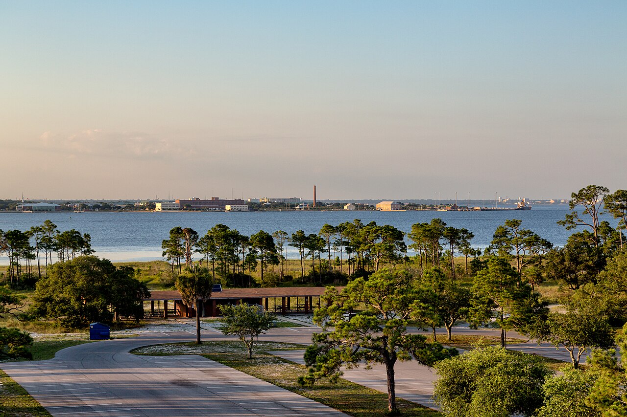 Fort Pickens picnic area, campground, and parking lot as seen from Battery Worth with Pensacola Beach, Florida, and the Pensacola Naval Complex/Pensacola NAS DRMO across the bay.