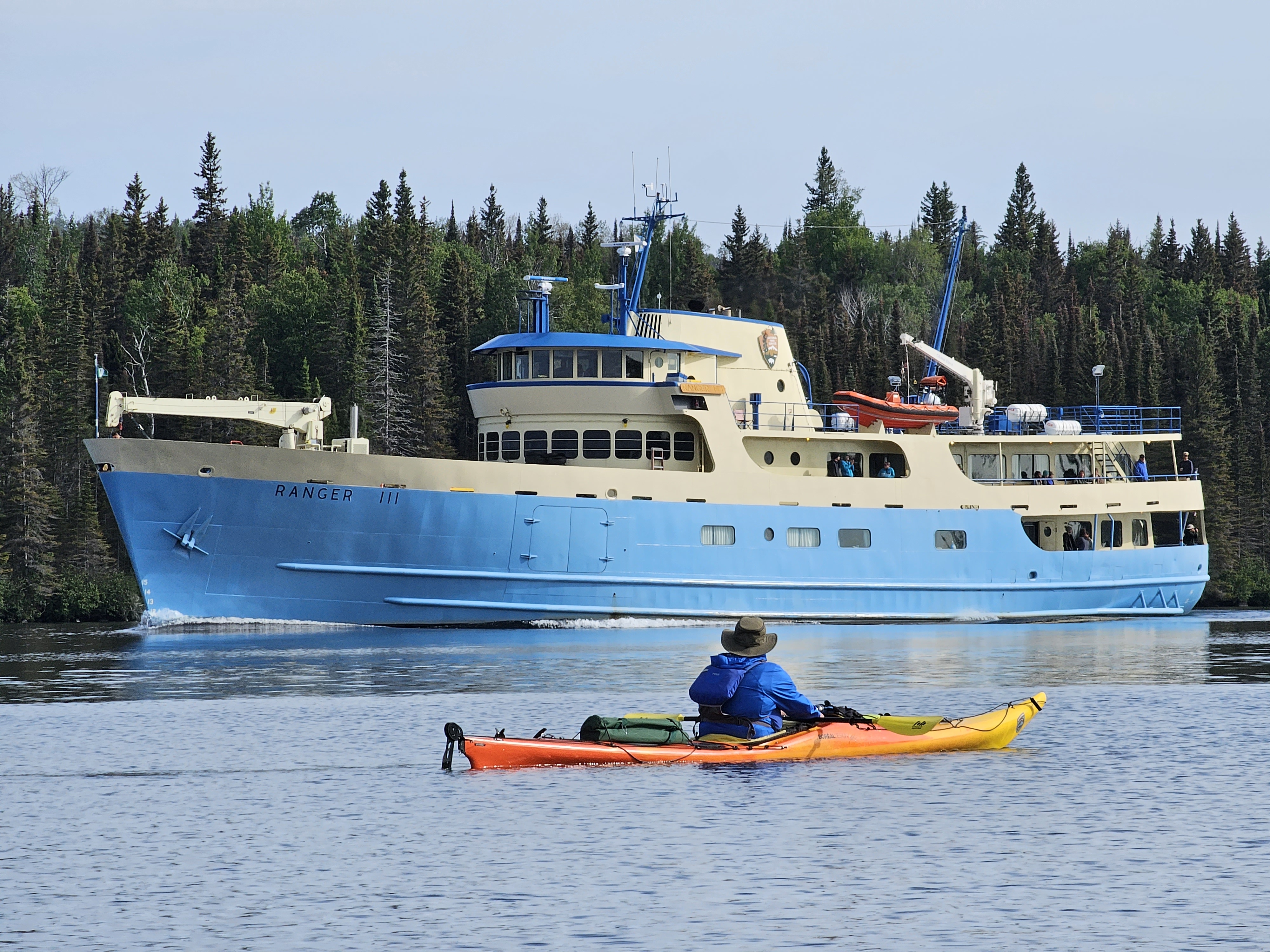 A man kayaking in front of Rock Harbor Lighthouse on a sunny day.