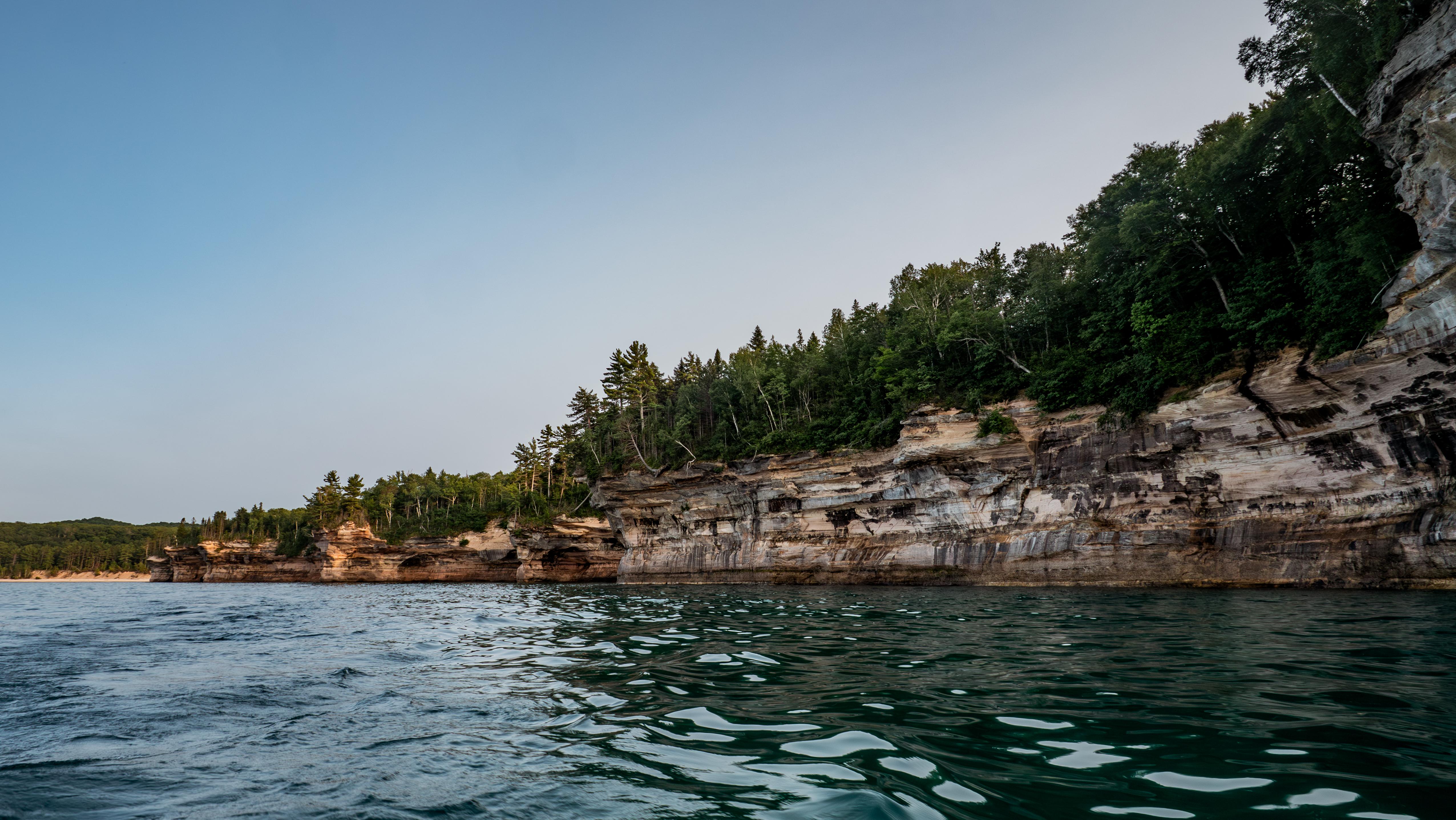 Multi-colored sandstone cliffs rise out of Lake Superior