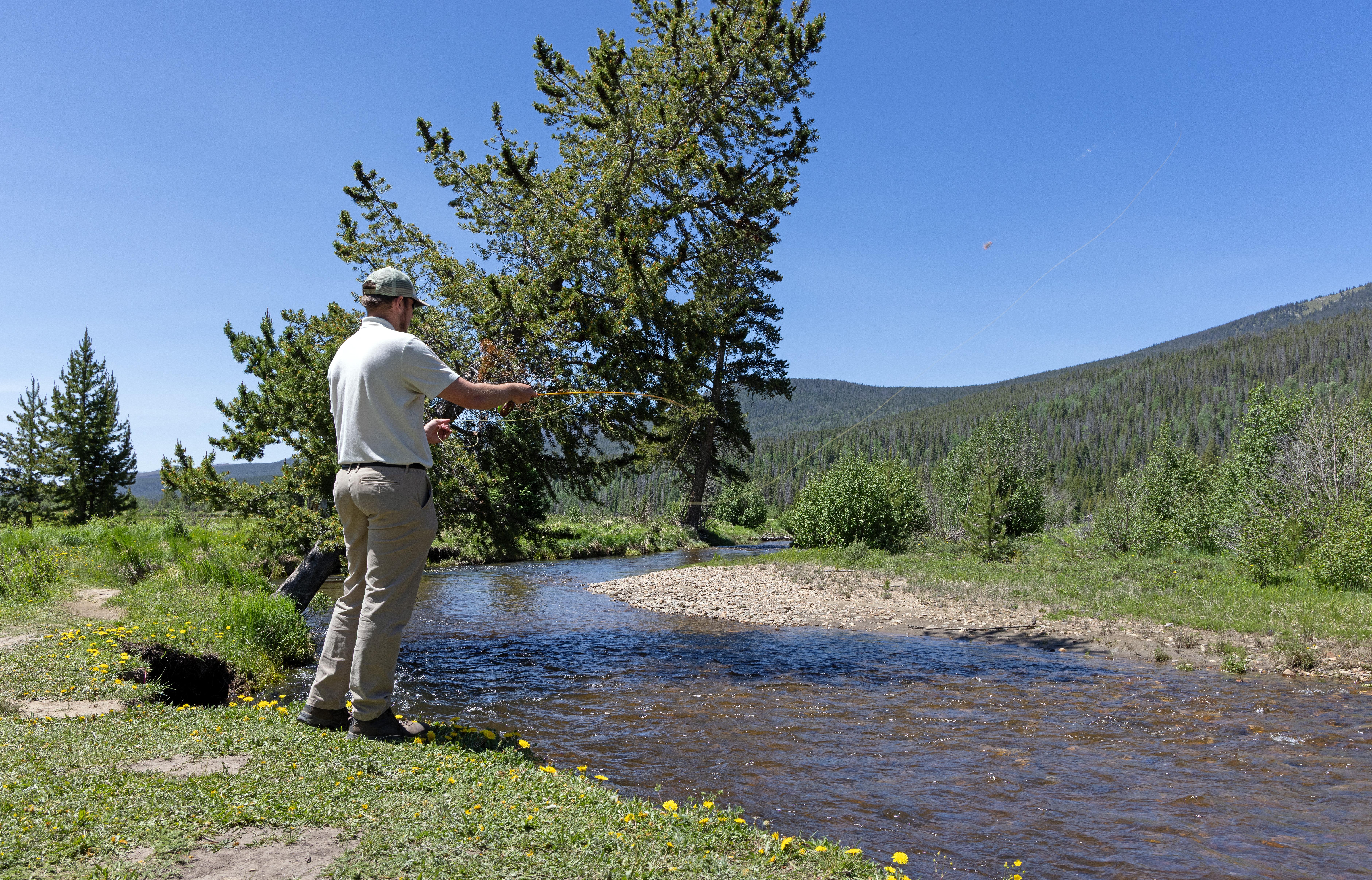 A man is fishing along the banks of a river