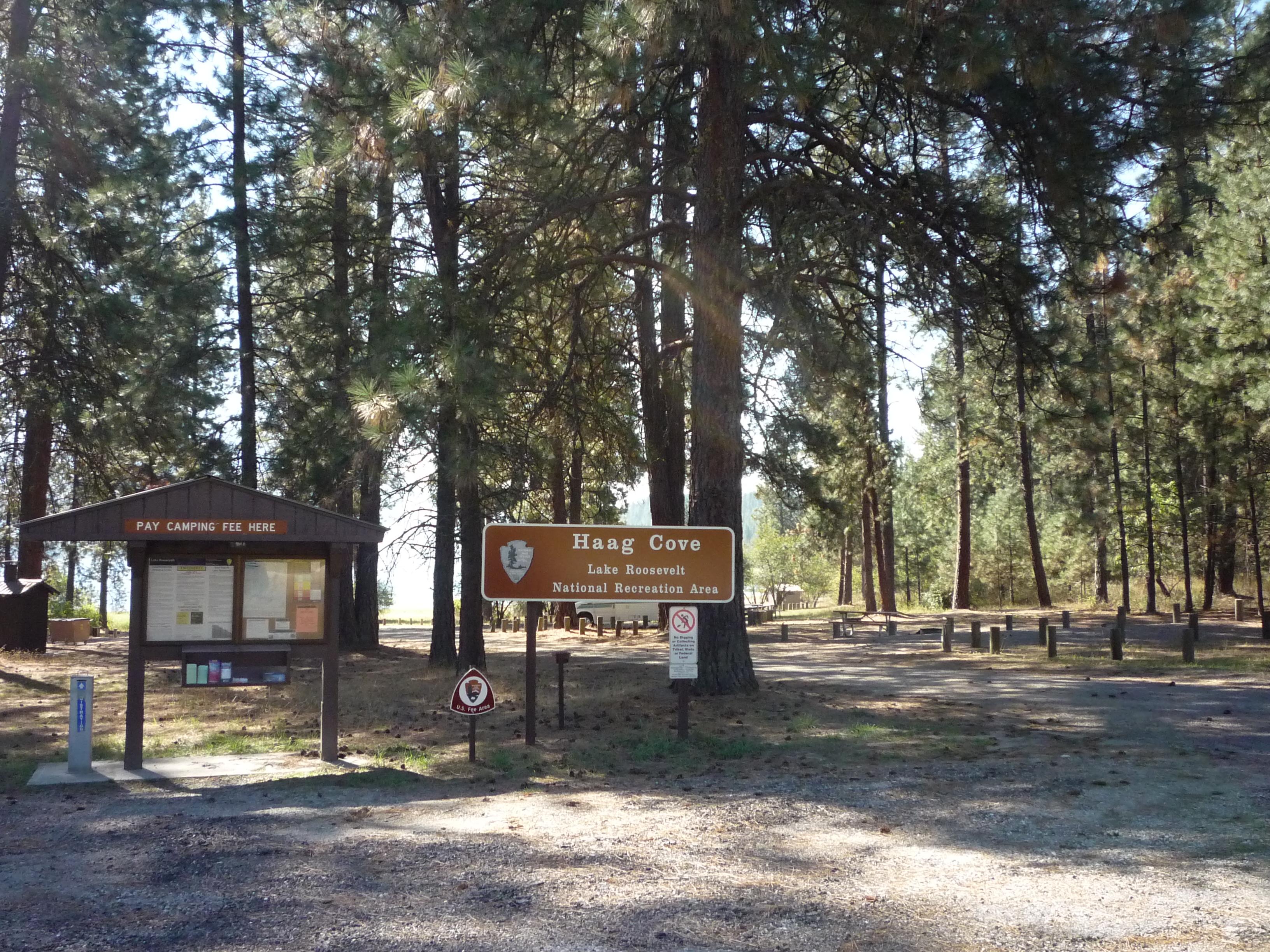 The campground bulletin board kiosk with the lake and campsites beyond.