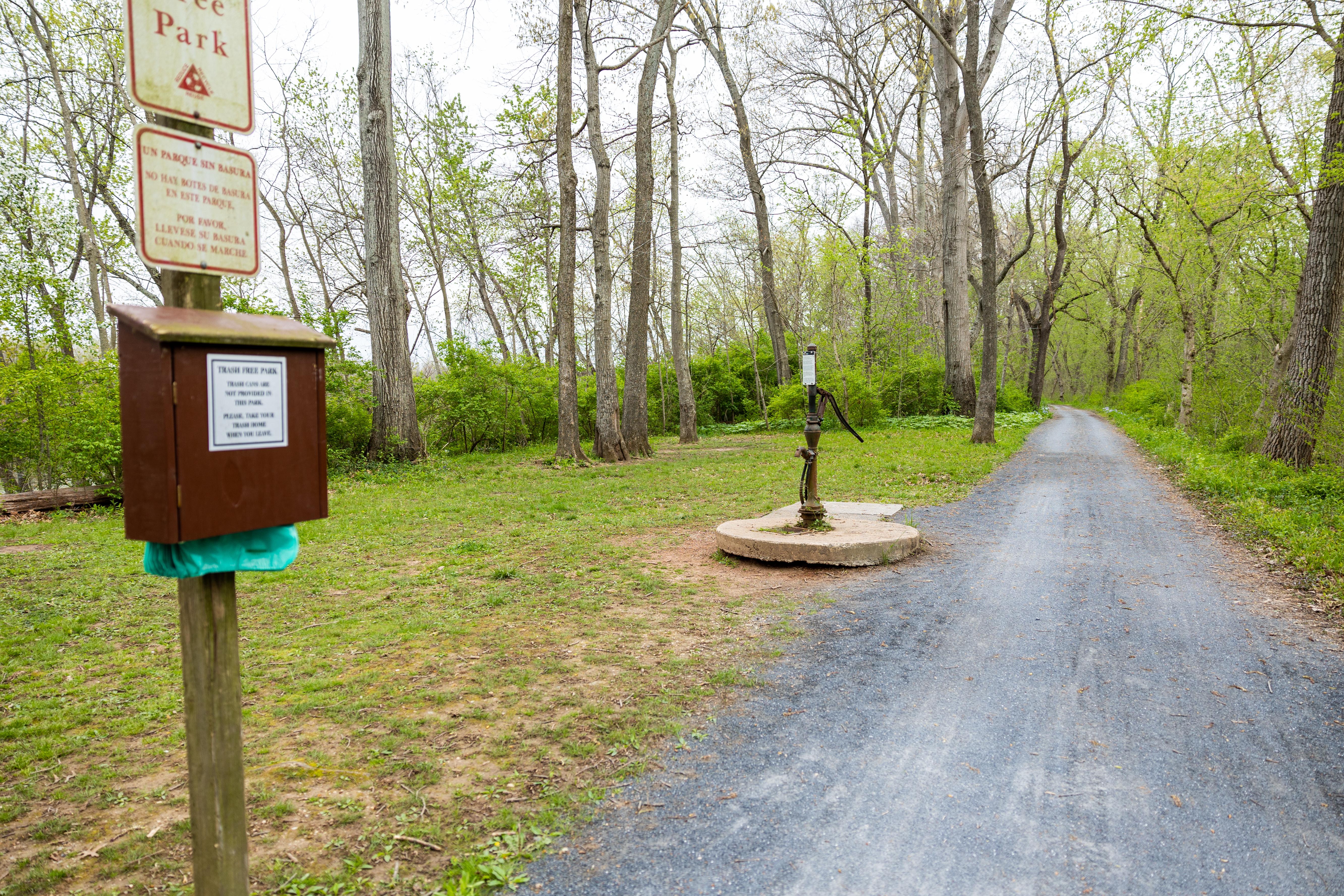 Campground with regulatory signs and water pump next to a trail
