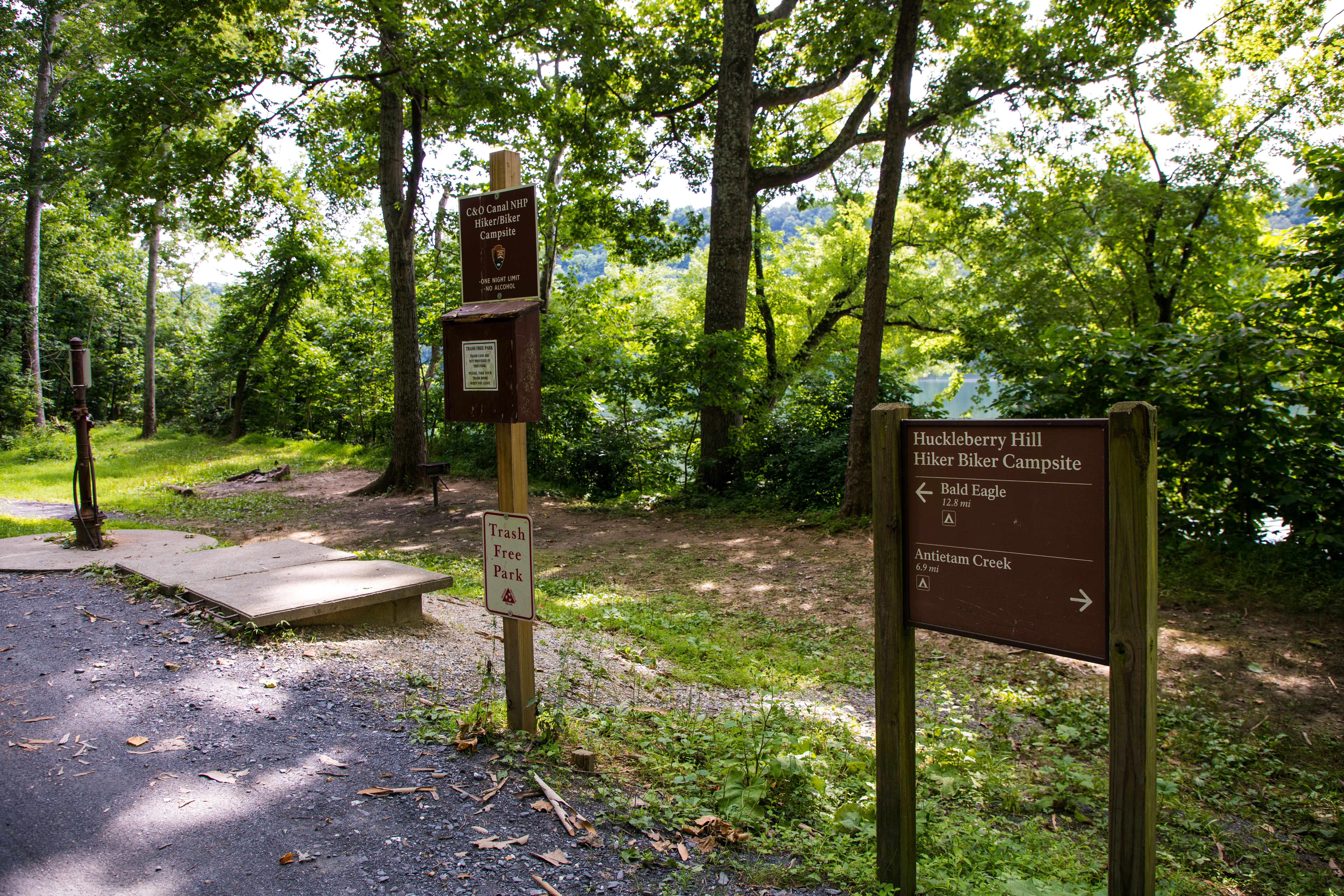 Campsite sign next to regulatory sign and water pump