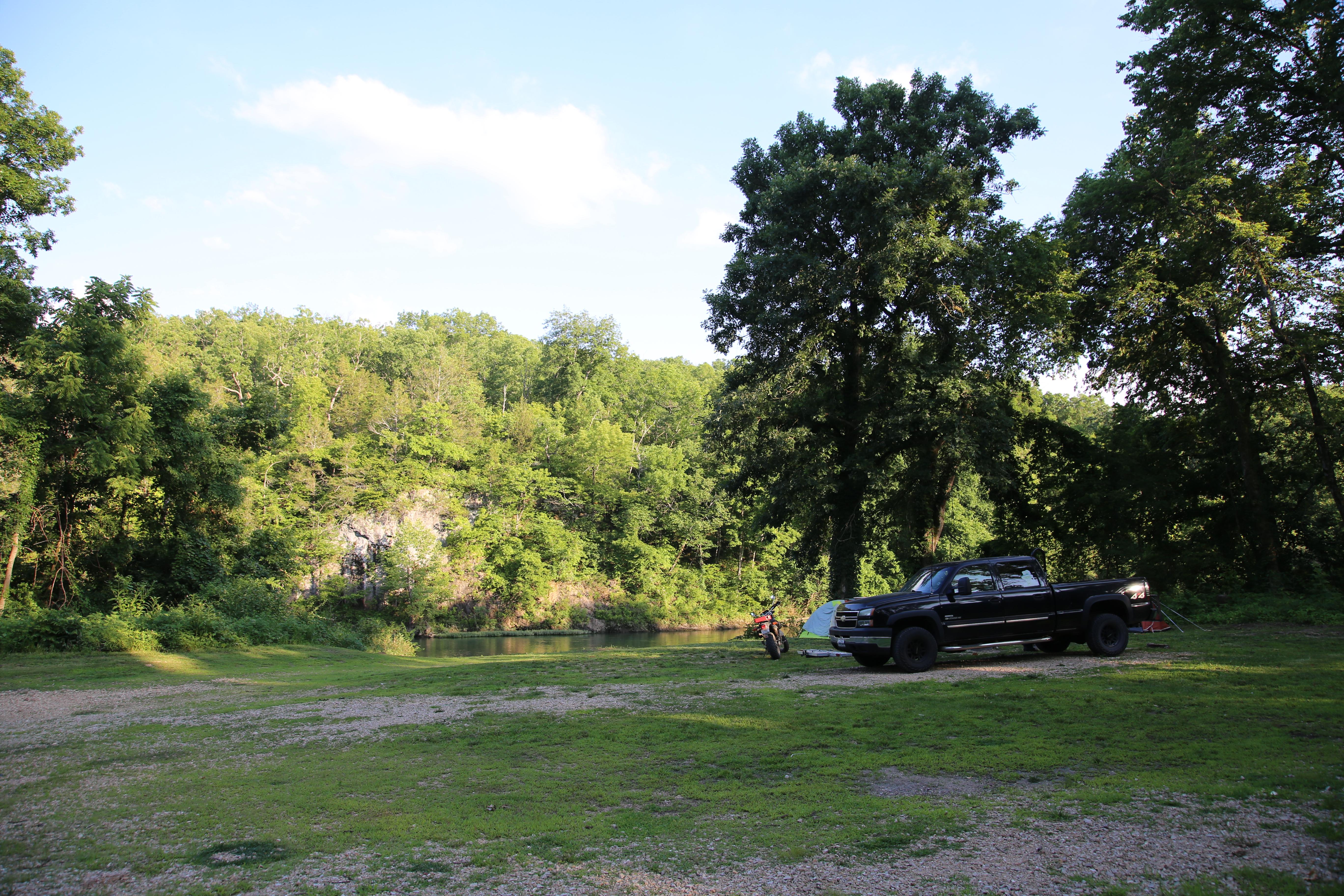 A tent and pickup truck occupy a campsite near the river's edge.