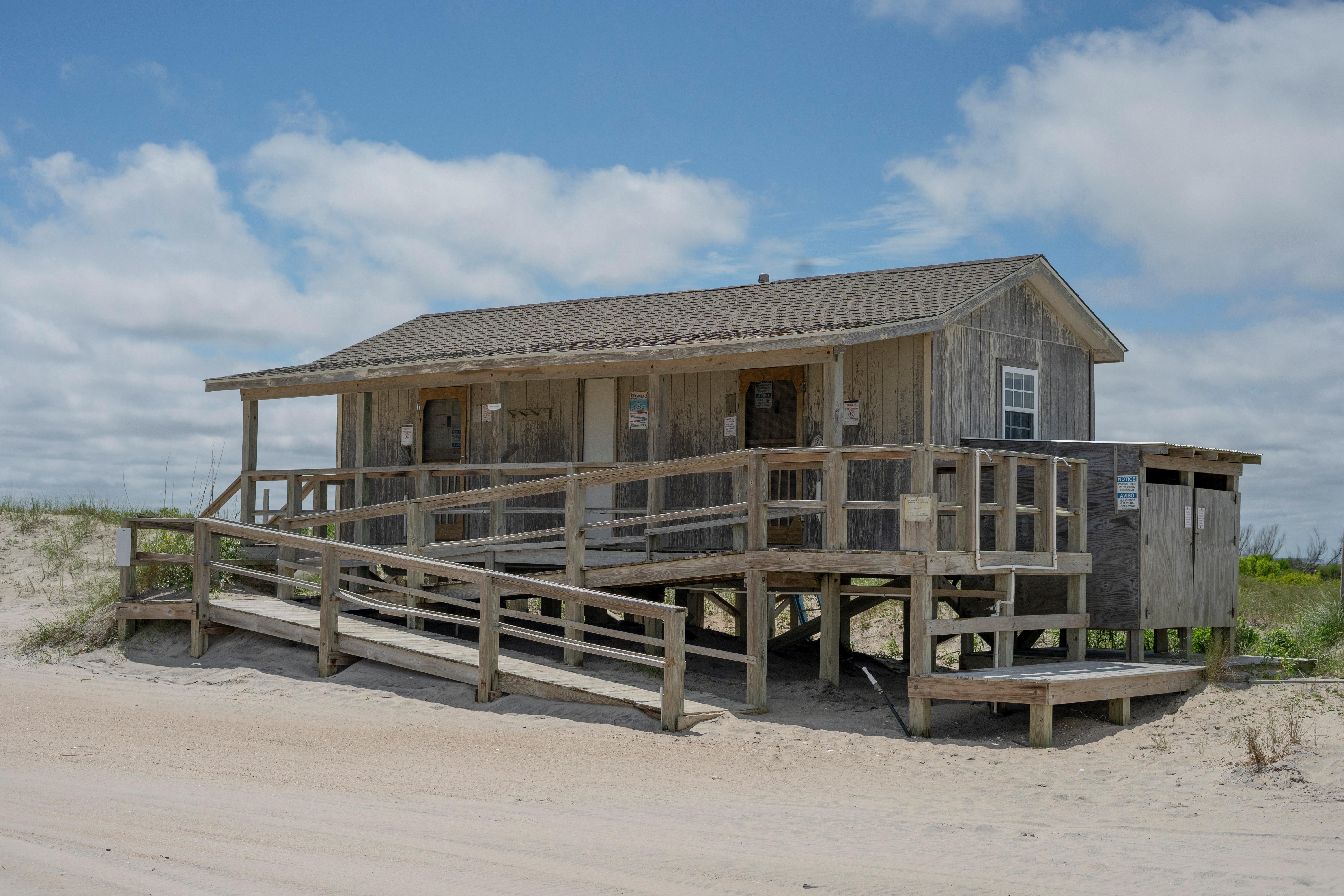 A small building with a wheelchair ramp in the sand.
