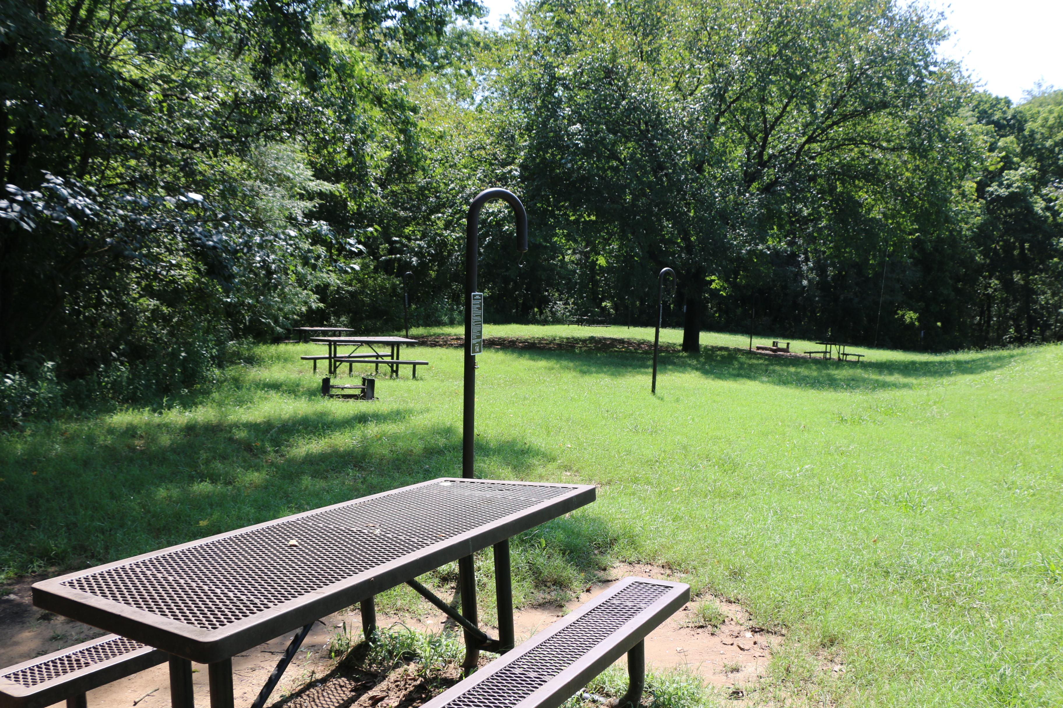 Four campsites with picnic tables and shade trees at Ozark Campground.